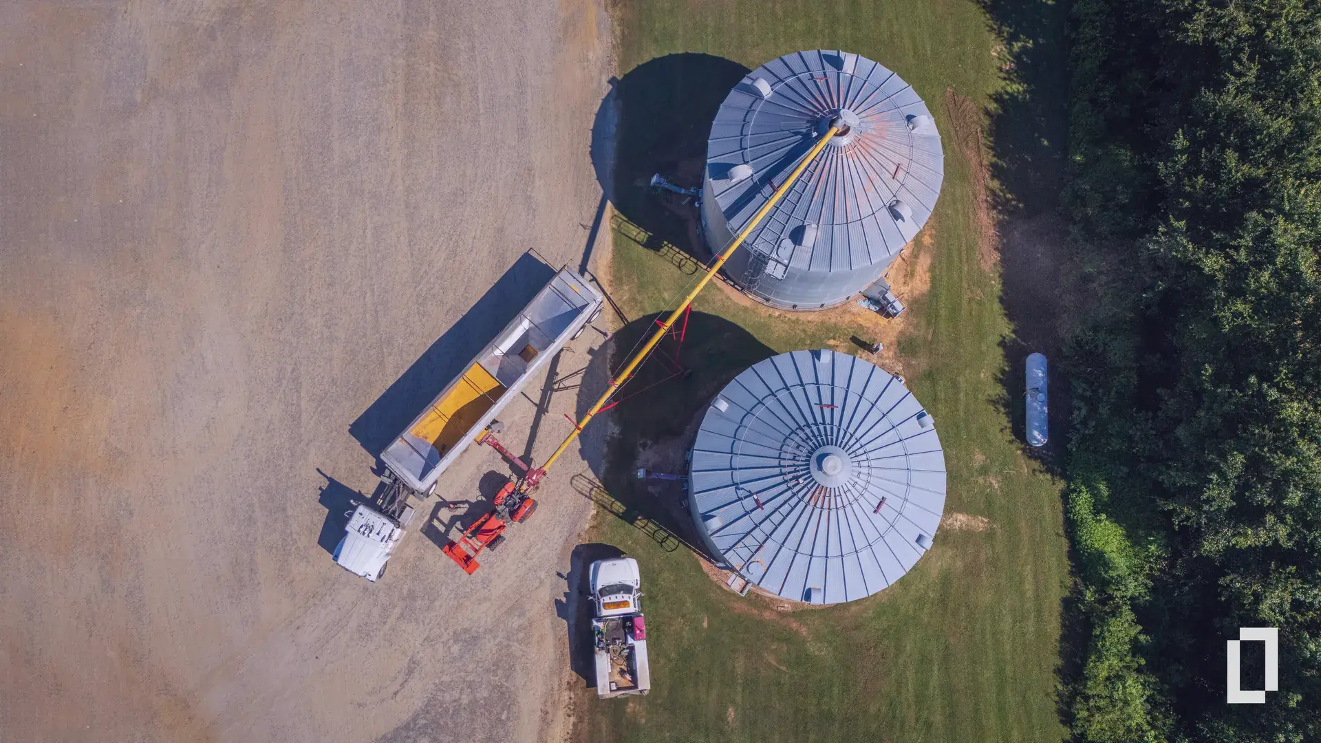 Aerial view of grain silos with a truck being loaded, the point where agricultural products enter a company's supply chain.